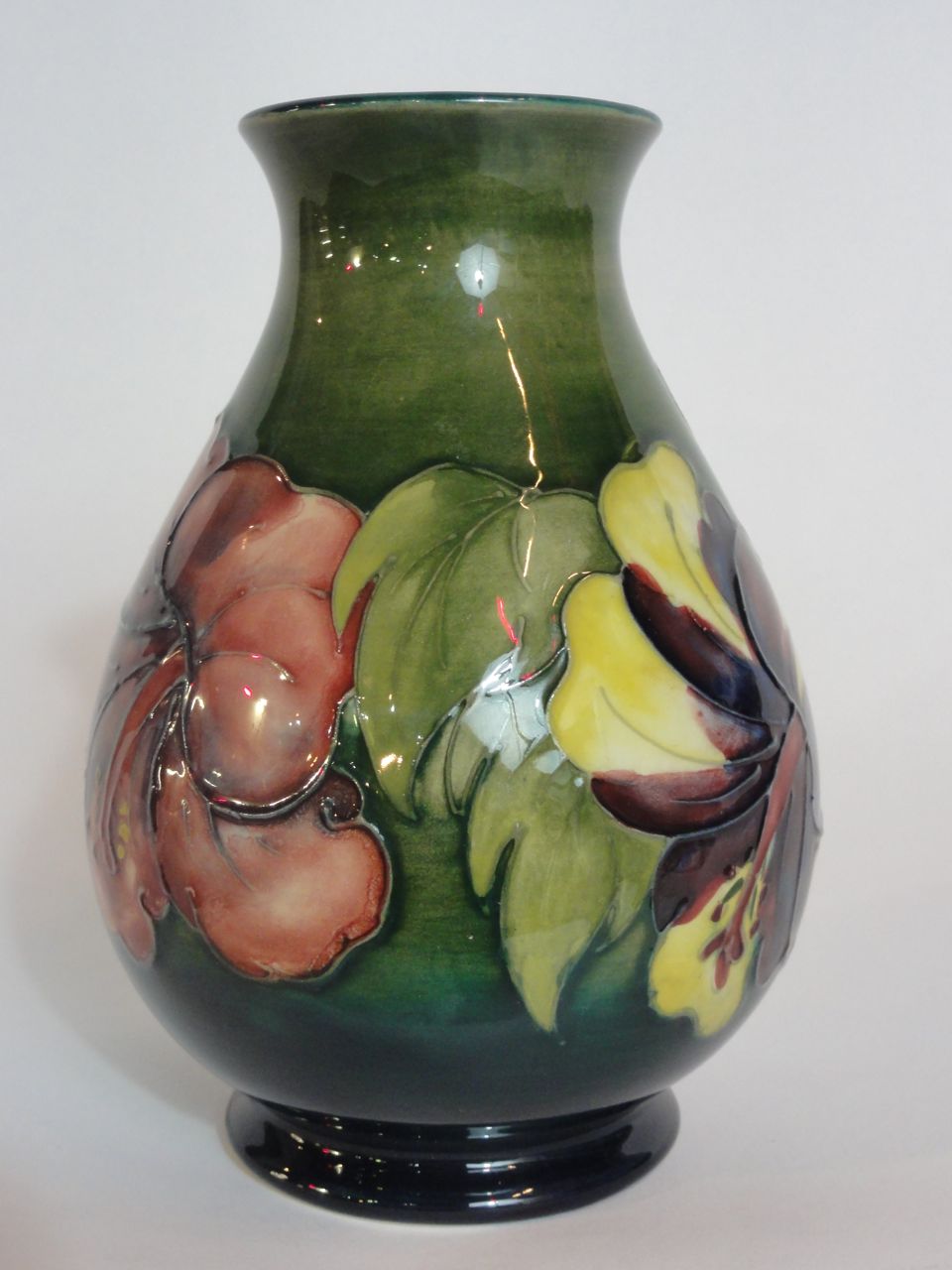A Moorcroft hibiscus pattern vase on a green ground, 13 cm high approx