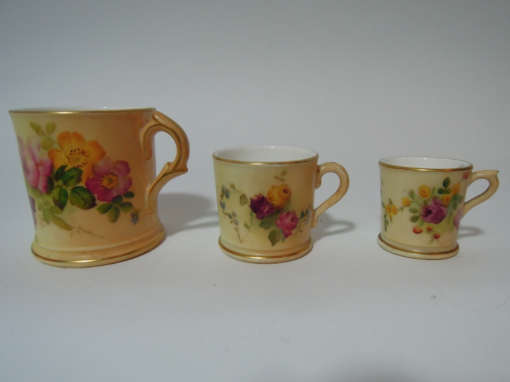 A graduated set of three Royal Worcester Blush Ivory mugs hand painted with floral decoration,
