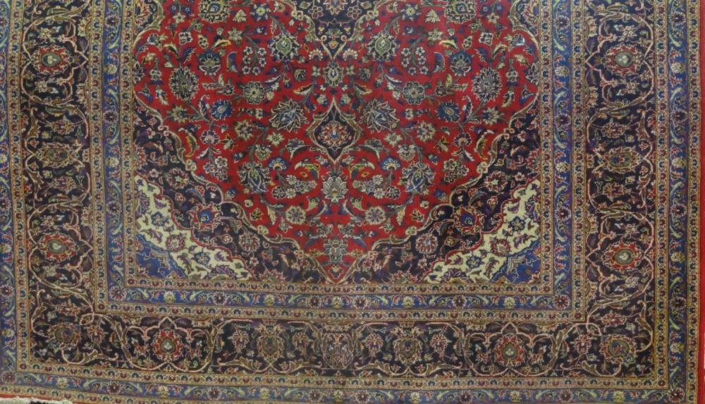 A Persian style carpet with alternating white and blue medallion upon a red field within further