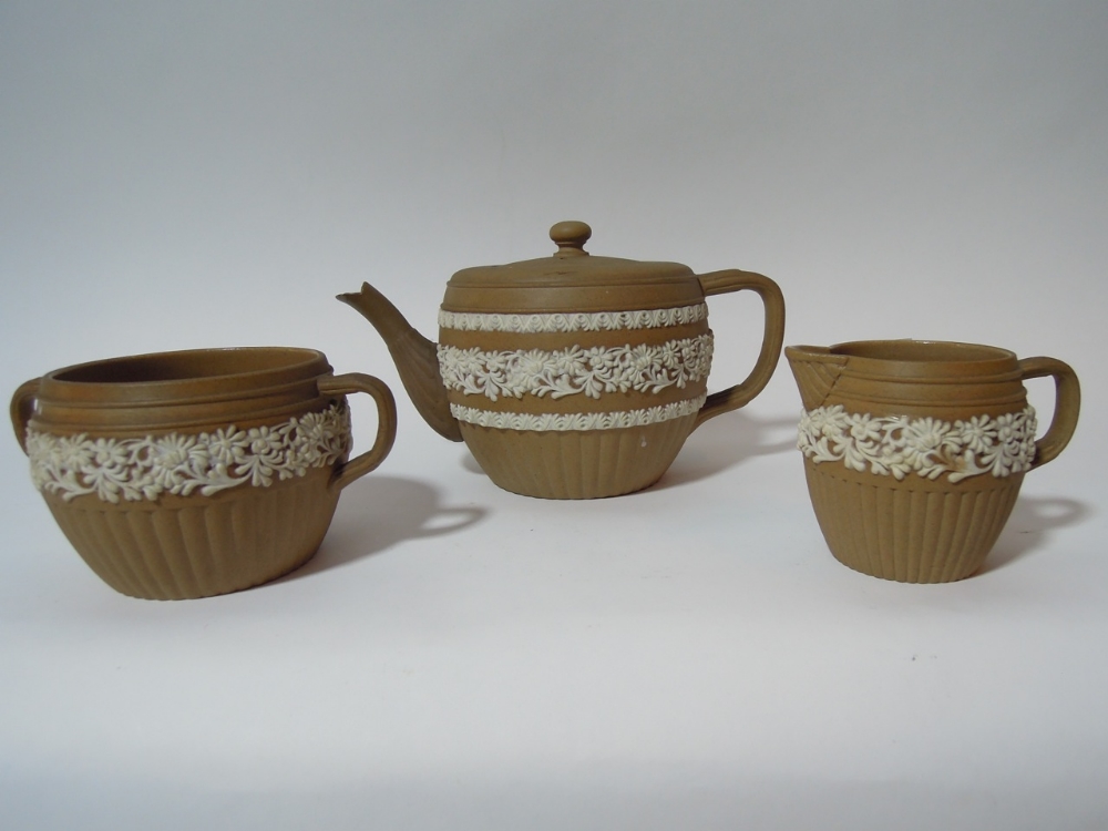 A three piece stoneware Royal Doulton silicone 1295 tea set in brown decorated with white floral