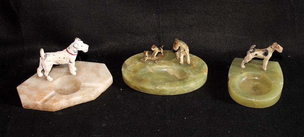 Three Art Deco cold painted metal model of dogs mounted on a hardstone onyx and alabaster ashtray