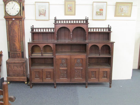 An Arts & Crafts walnut side cabinet with carved sunflower and arcaded decoration on turned legs, w.