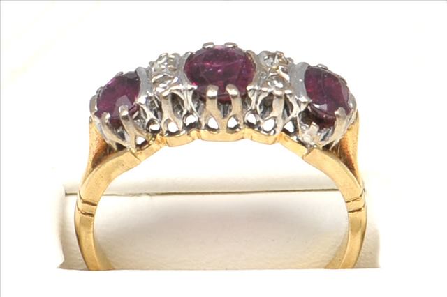 A THREE STONE RUBY AND DIAMOND RING, in 18ct gold consisting of three oval rubies central set with