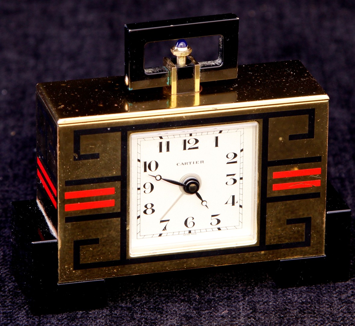 An early 20th century Art Deco style Cartier travelling clock with geometric decoration upon a brass