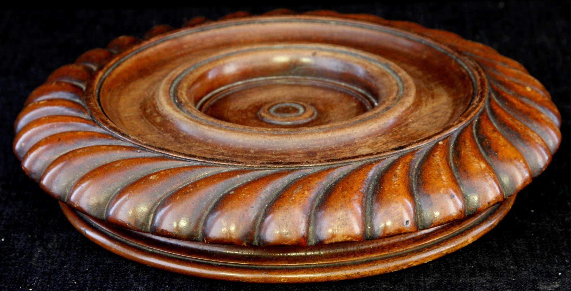 A 19th century carved mahogany wine bottle coaster with carved border and three roller castor