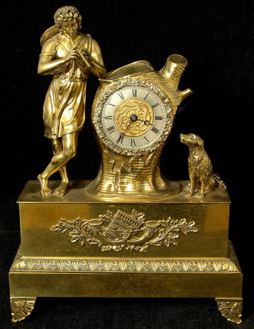 A 19th century French Empire style gilt-brass cased mantel clock depicting a figure playing pipes