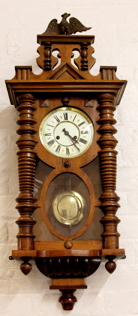 An early 20th century walnut cased Vienna wall clock with Roman numeral cream dial and carved column