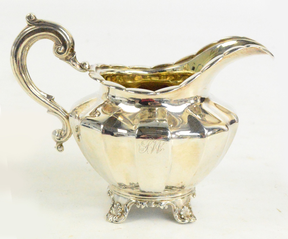 An early Victorian hallmarked silver milk jug of panelled circular form with gilt washed interior