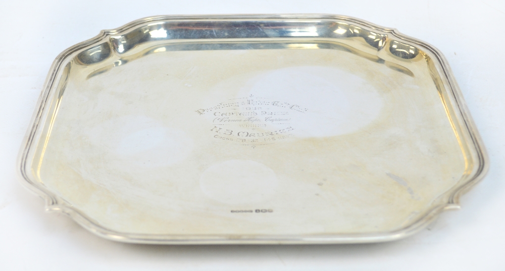 A George V hallmarked silver square section salver raised on squat bun supports, the centre engraved
