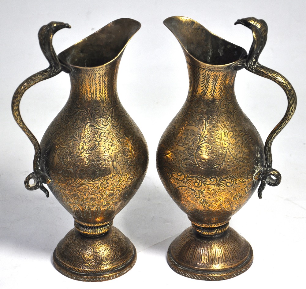 A pair of late 19th century Indian brass jugs with cobra handles and all over engraved decoration,