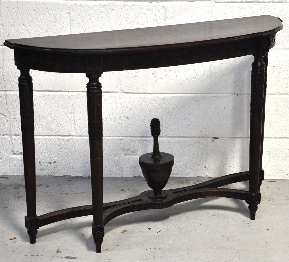 A reproduction mahogany bowfronted hall table with carved fluted legs united by a shaped