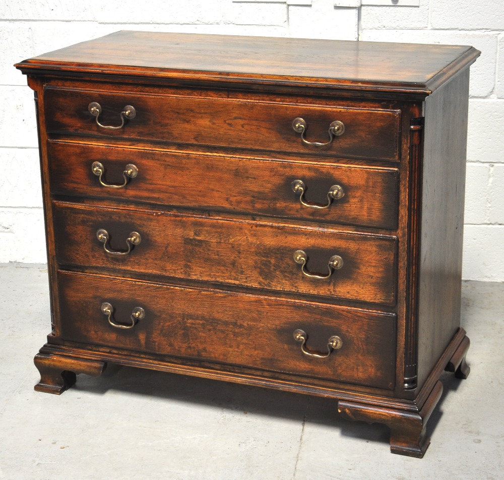 A good quality reproduction oak chest of four long graduated drawers flanked by fluted quarter cut