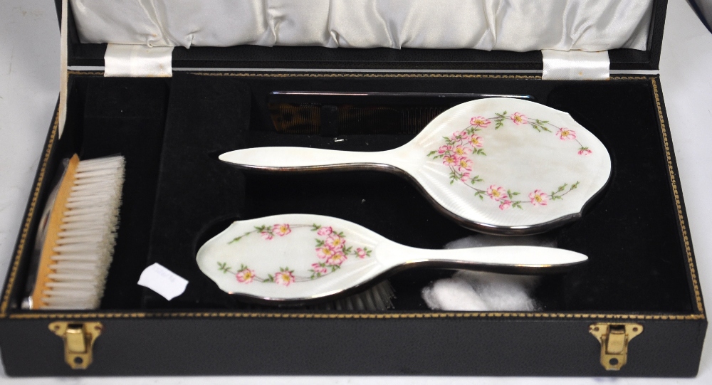 An Elizabeth II cased hallmarked silver and guilloche brush, mirror and comb dressing table set,