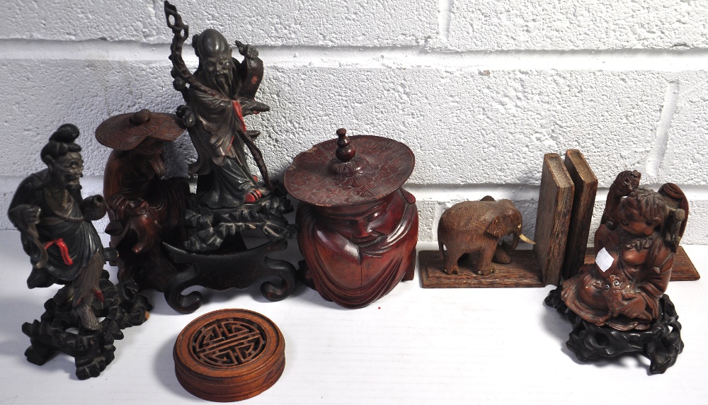 Four Oriental treen figures, a pair of treen bookends with elephants and another treen jar with