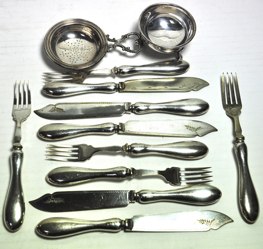 A white metal tea strainer with stand, a cased set of George VI silver handled knives and forks