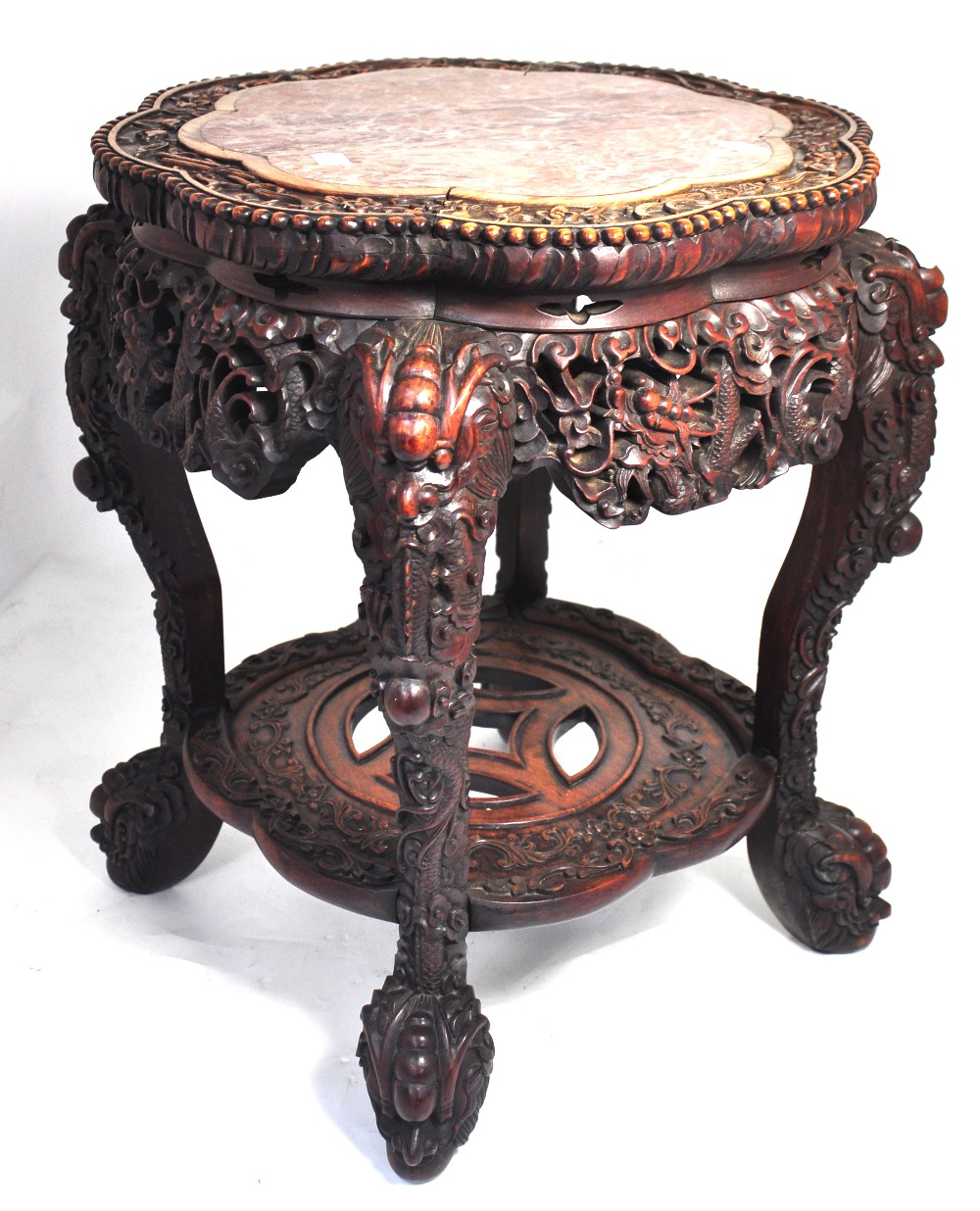 A late 19th century Chinese profusely carved hardwood jardiniere stand, with rouge marbled top above