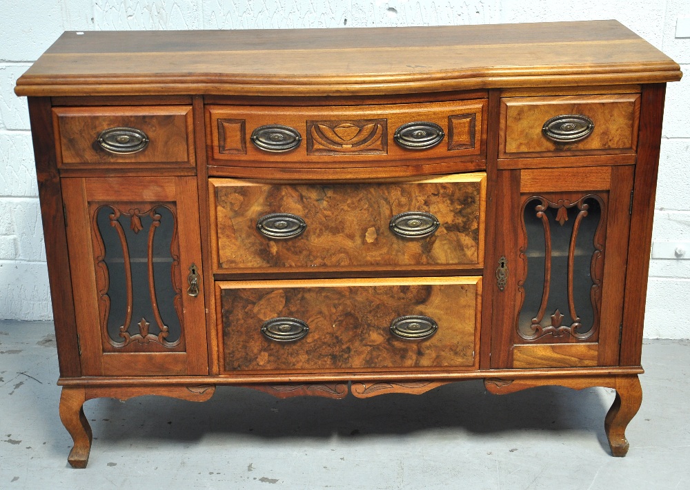 A 20th century walnut bow fronted sideboard, three central drawers flanked by twin cupboards, raised