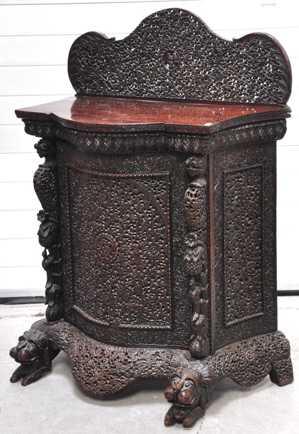 A Burmese heavily carved bow fronted cabinet resting on dragon feet with ornate moulded top, 125 x