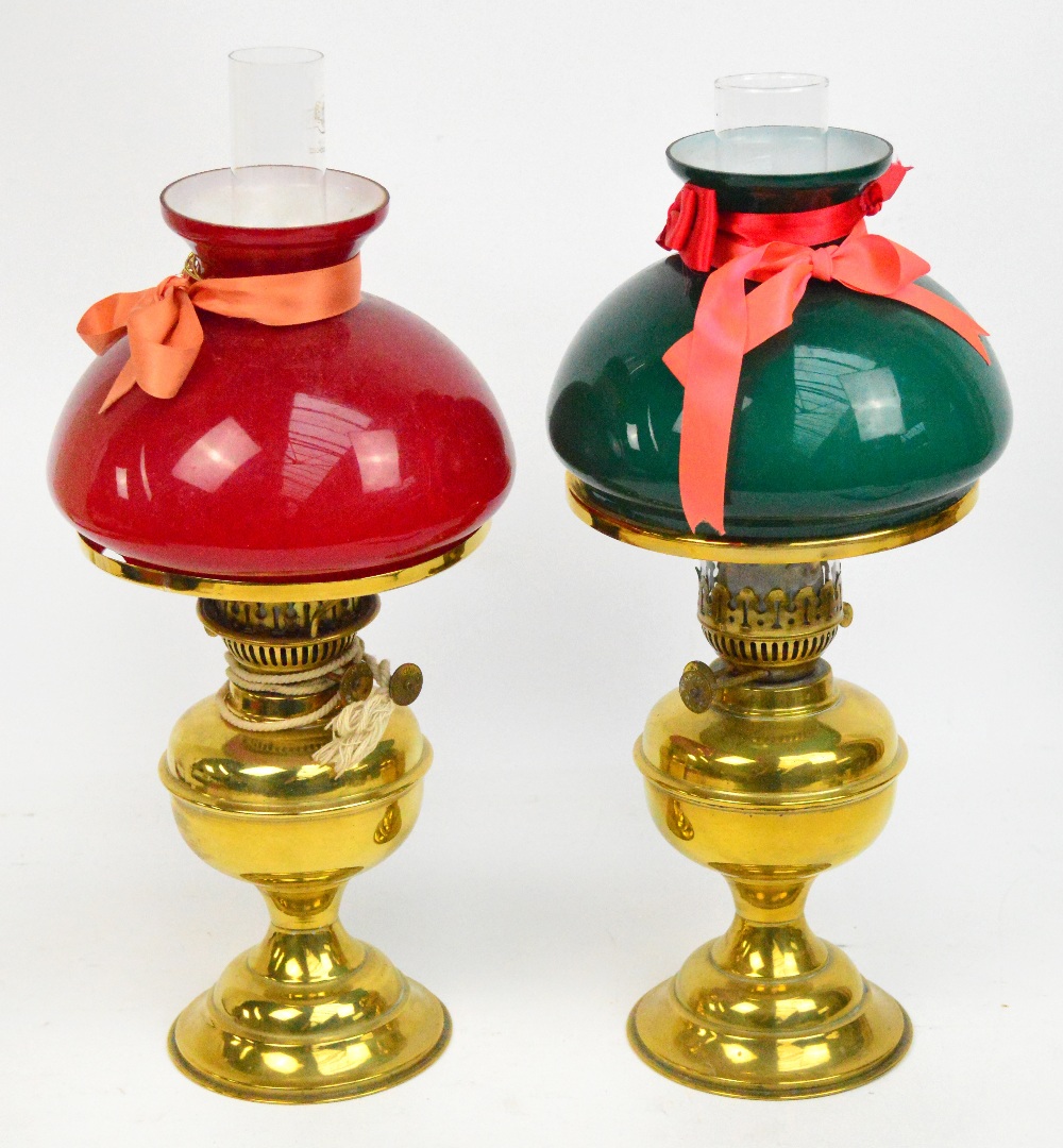 Two brass oil lamps with glass sleeve and shade.