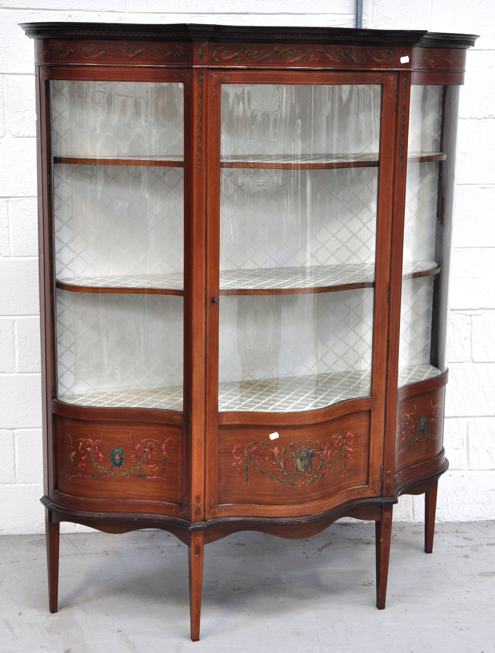 An Edwardian serpentine fronted string decorated display cabinet with Greek key decoration to the