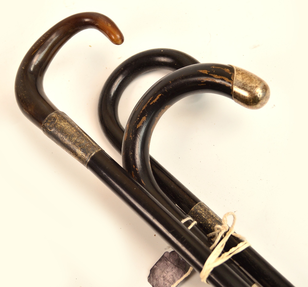 Three ebonised walking canes with silver mounts, one with horn handle.