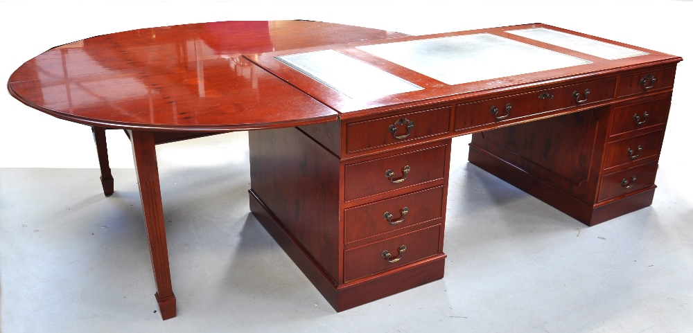 A reproduction pedestal desk with leather top and an associated circular adjoining table, diameter