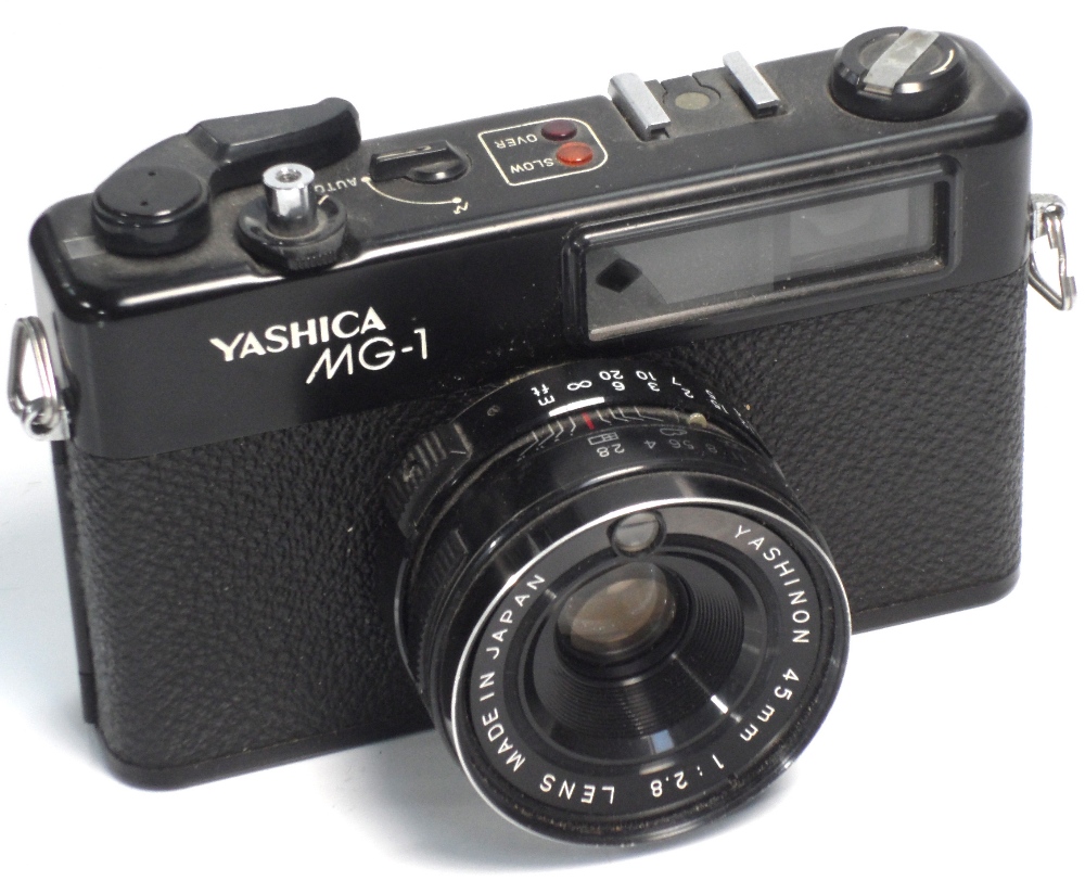 A Yashica MG-1 35mm range finder camera and several other compact 35mm cameras.