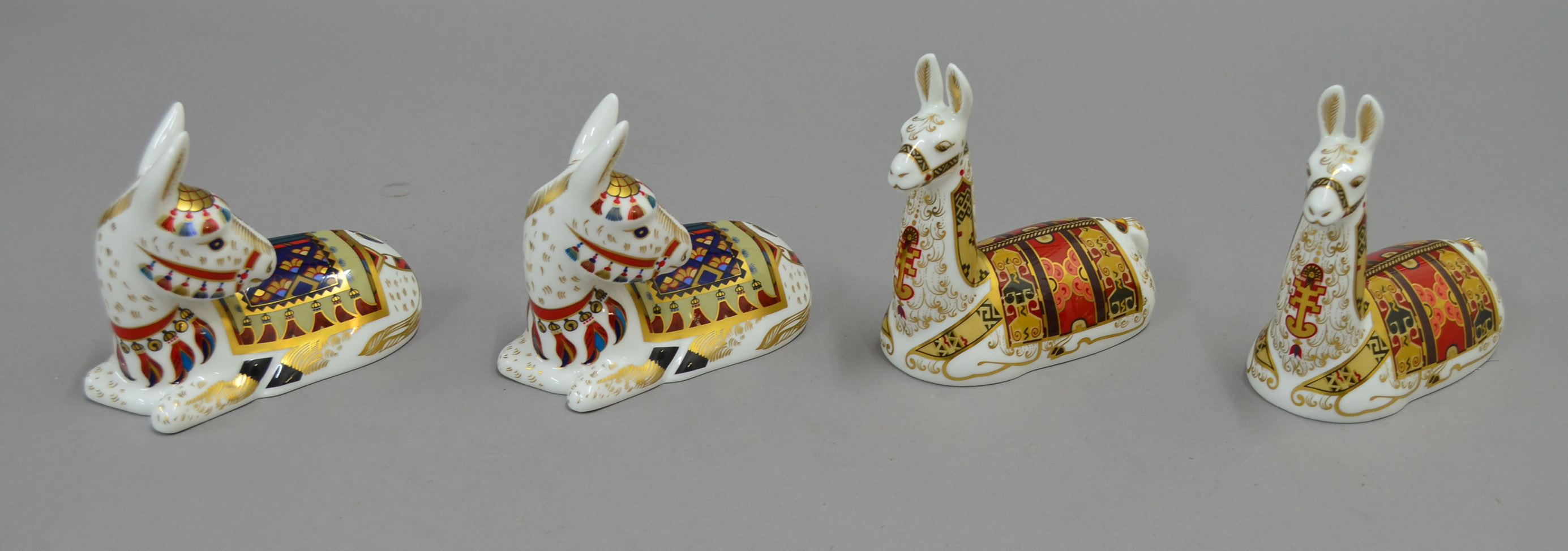 Two exclusive Royal Crown Derby `Llama` paperweights, together with two donkey paperweights. All