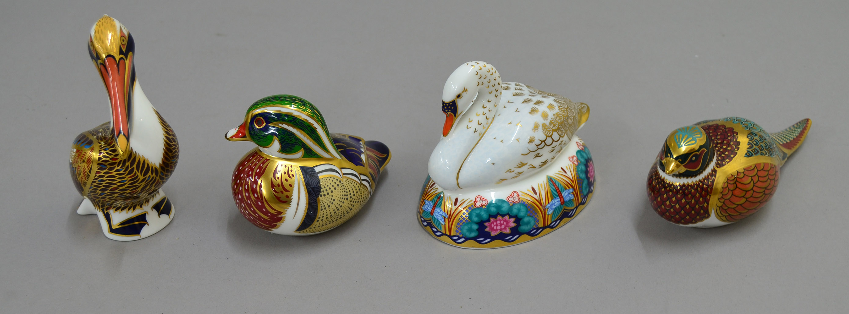 Four Royal Crown Derby bird paperweights including `Brown Pelican`, `Woodland Pheasant`, `Carolina