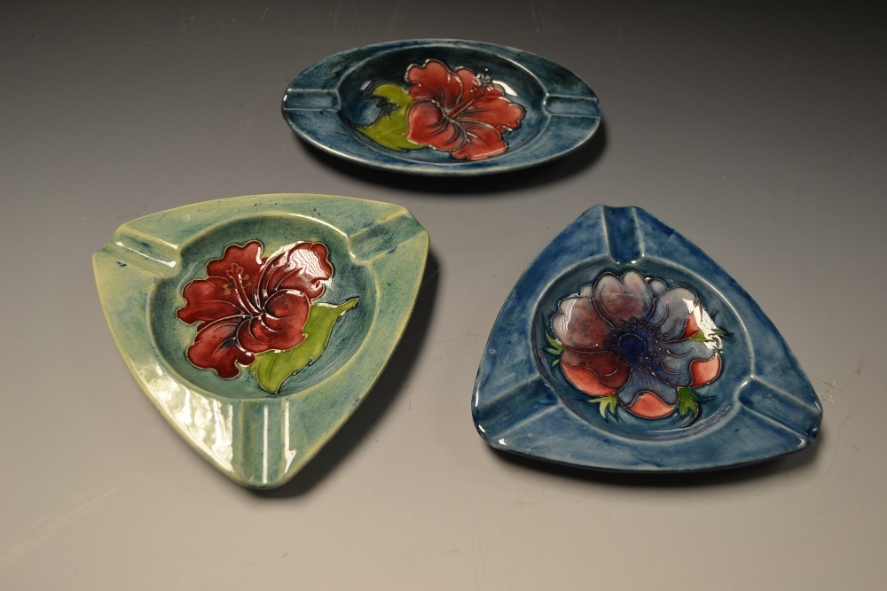 A Moorcroft pottery Hibuscus triangular ashtray; another oval; 
a Moorcroft Anenome triangular