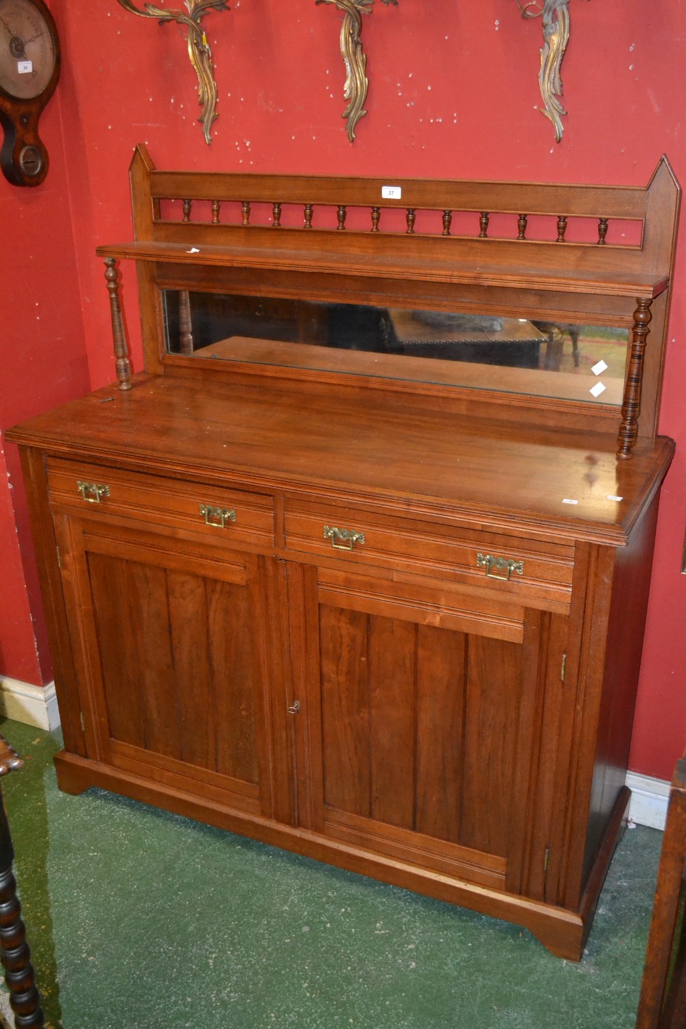 An Edwardian walnut mirror backed chiffonier, spindled gallery, shelf supported by turned columns,