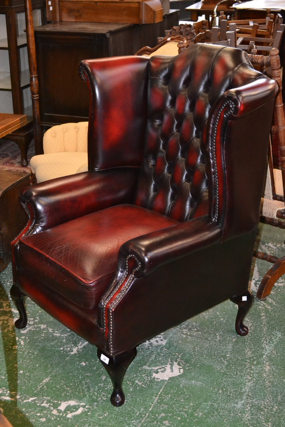 An oxblood leather wingback chair, deep button upholstery.