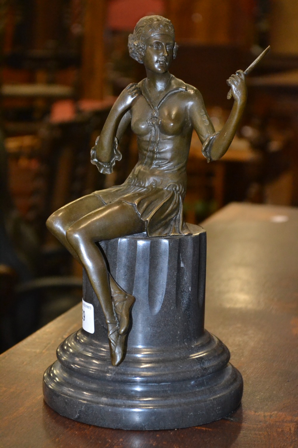 A bronze figure; study of a young lady, she sits a top marble column admiring her reflection, 28cm