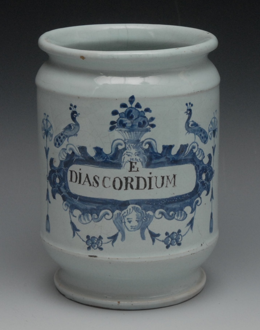 An 18th century Delft dry drug jar, inscribed E. DIASCORDIUM within a cartouche centred by a mask