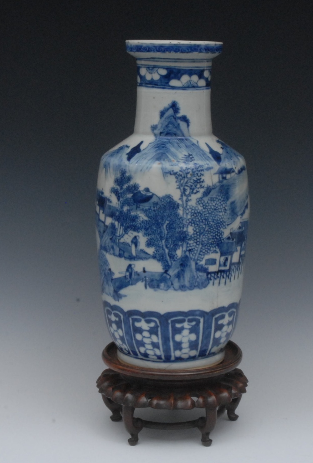A Chinese blue and white rouleau vase, decorated with a continuous scene of figures, huts, pine tree