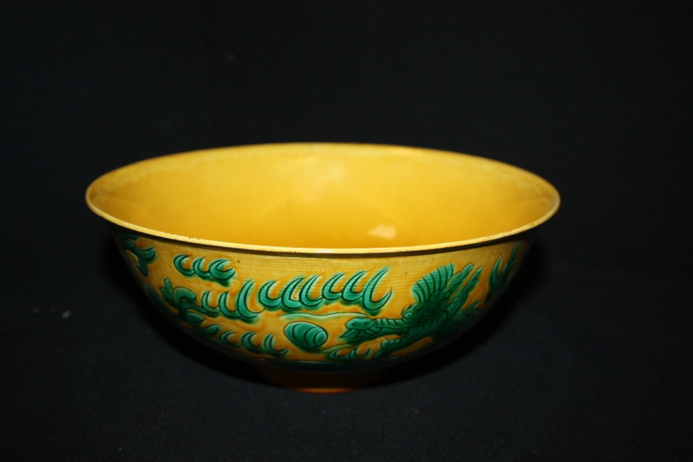 A Chinese pottery circular footed bowl, decorated with a green dragon on a yellow ground, Kangxi