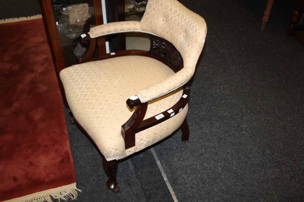 A late Victorian circular salon chair, stuffed back and seat, splat carved in relief with foliage,