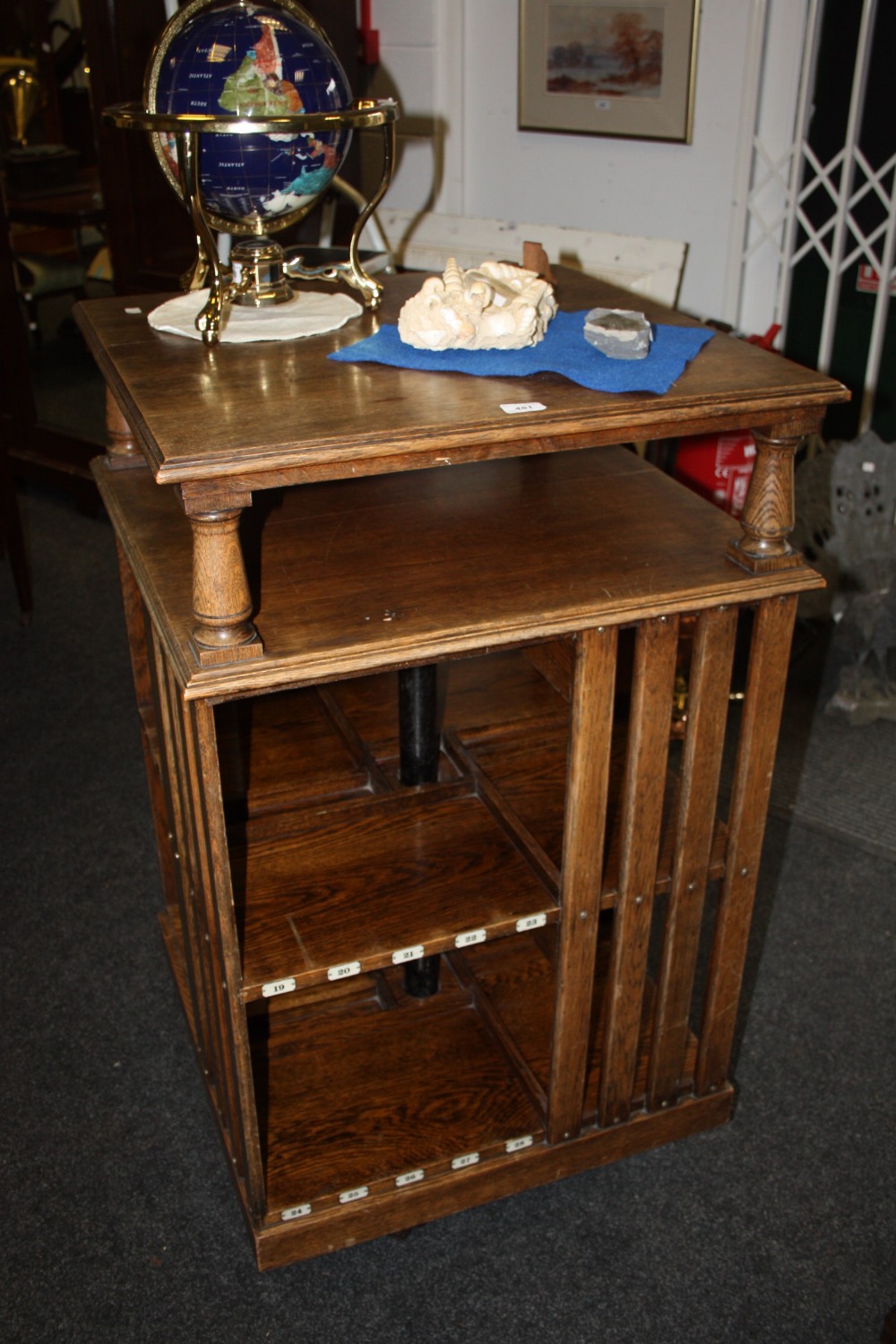 An early 20th century revolving bookcase, three shelves, two with pierced fretwork, applied with