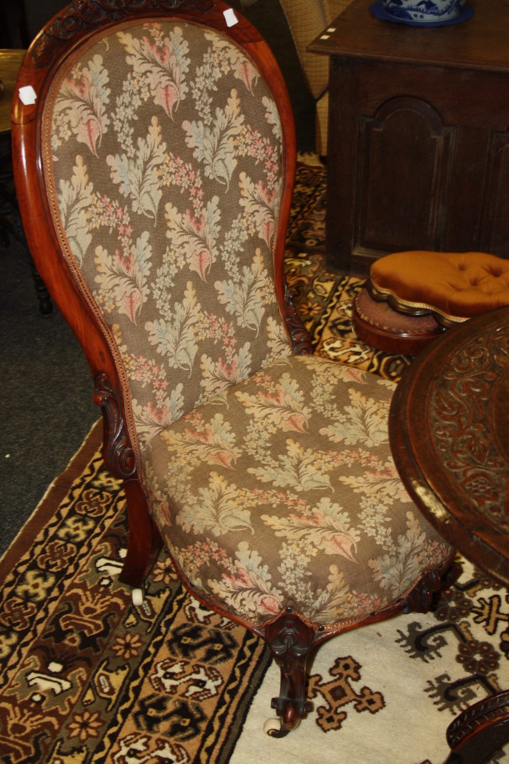 A Victorian balloon back walnut nursing chair, ornately carved feet, castors, c.1860