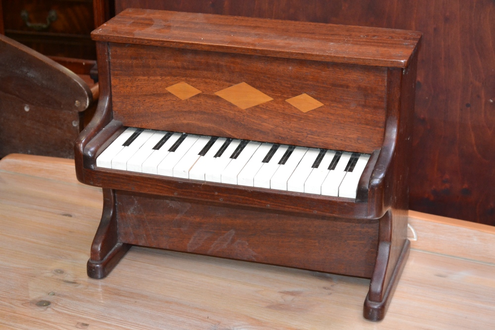 An early 20th century mahogany and marquetry child's model upright piano, slightly oversailing