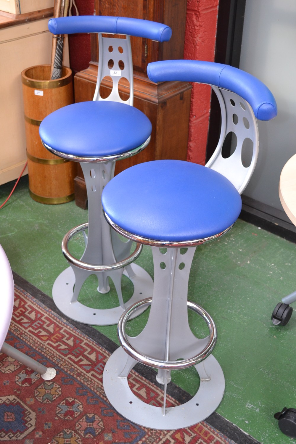 Two contemporary steel bar stools, blue leatherette top rail and circular seats, pierced metal