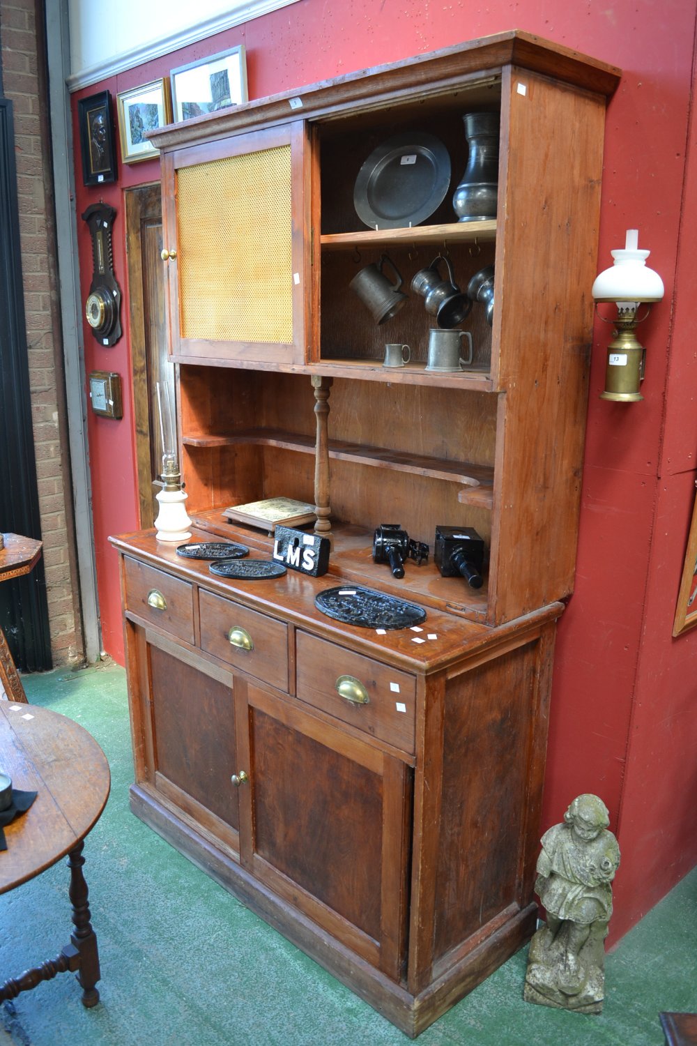 A stained pine kitchen dresser, fretworked metal sliding door cupboard over recessed shelving to