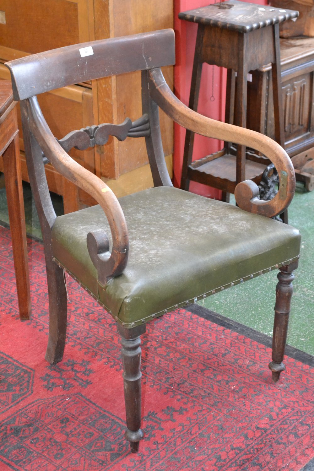 A scroll arm carver, curved top rail, carved horizontal splat, stuffed overseat, turned forelegs.