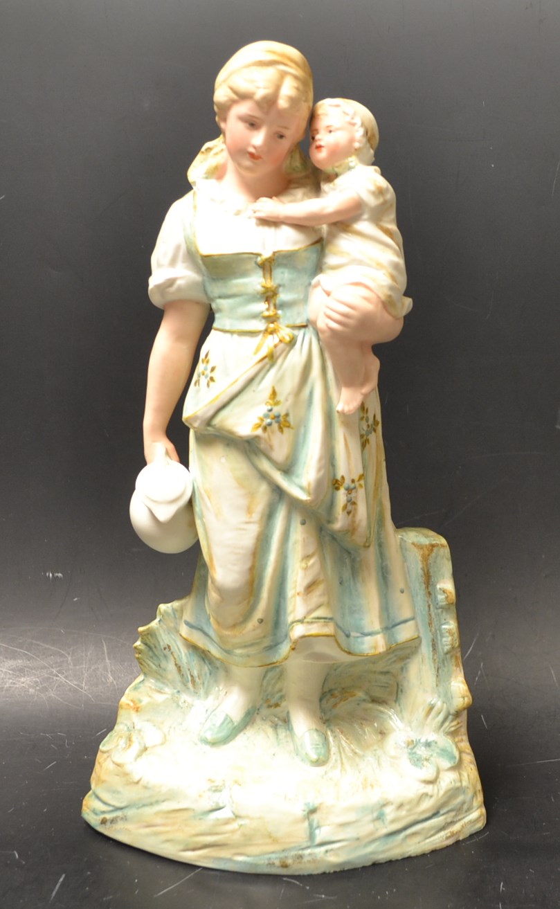A Gebruder Heubach (Germany) bisque figural group of a lady carrying her child, the other hand
