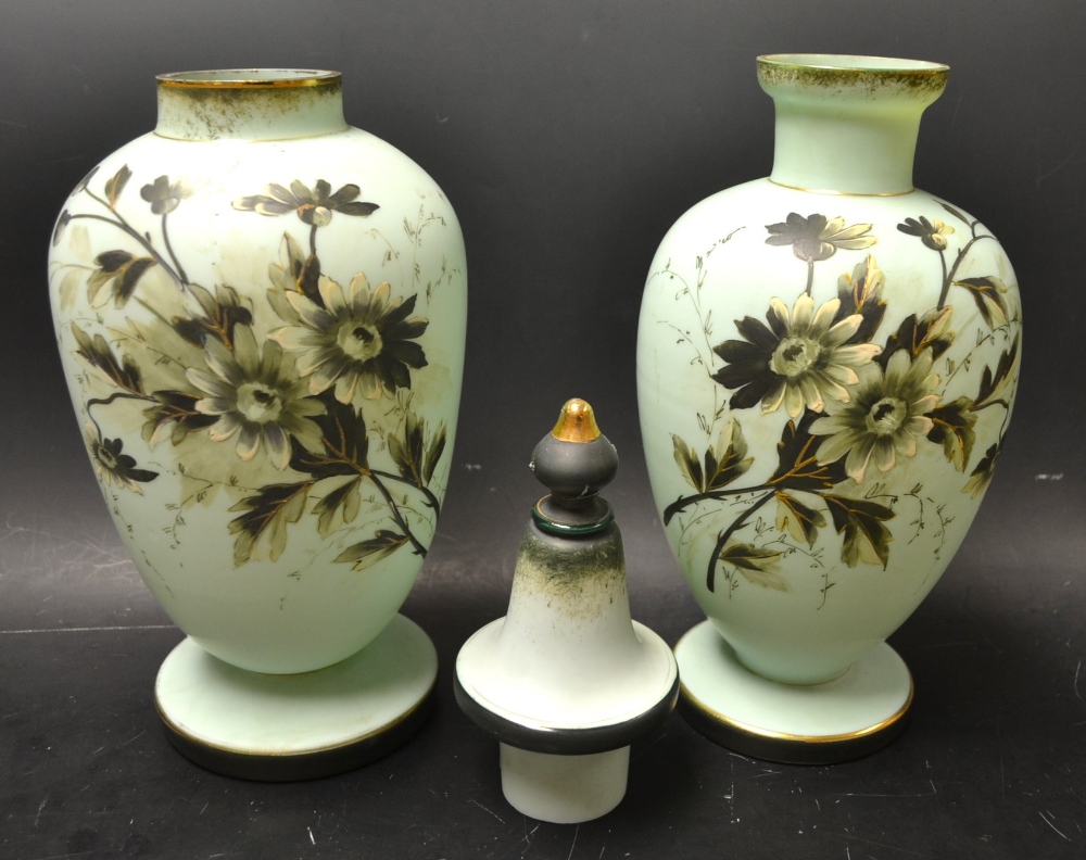 A near pair of satin glass vases, enamelled in black and white with flowers, on a blue ground,