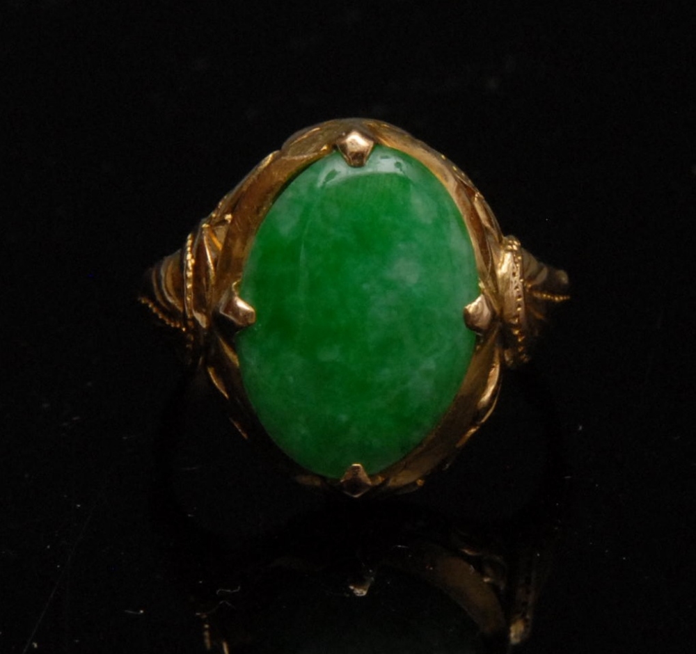 A green jadeite dress ring, the oval multi-tonal green jadeite cabochon, approx. 14mm x 10mm,