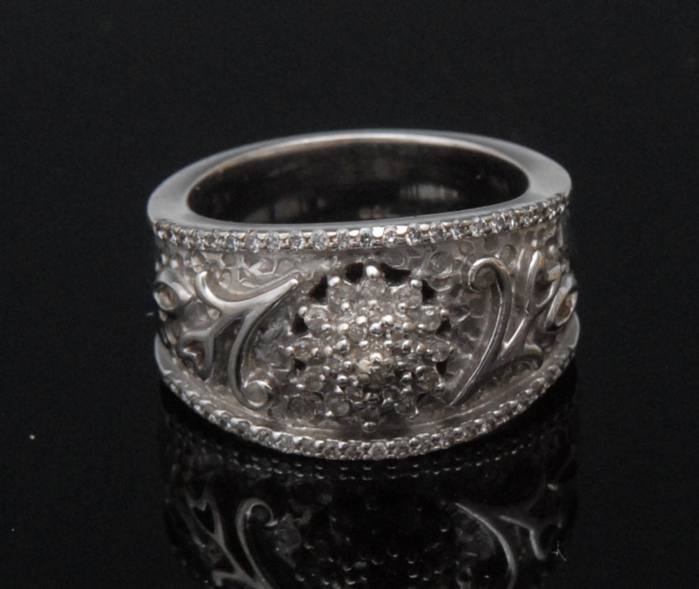 A 20th century diamond ring, central triple step diamond pinnacle within a scaled and foliate