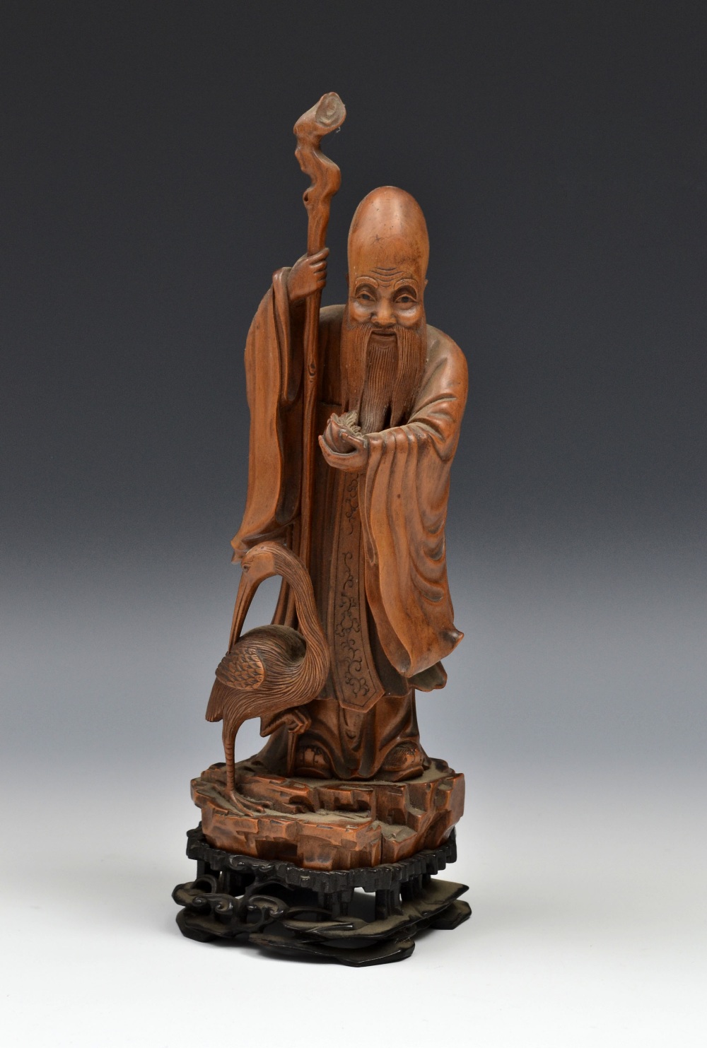 A Chinese boxwood carving, of Shou Lao, he stands, with staff and peach, a crane at his feet,
