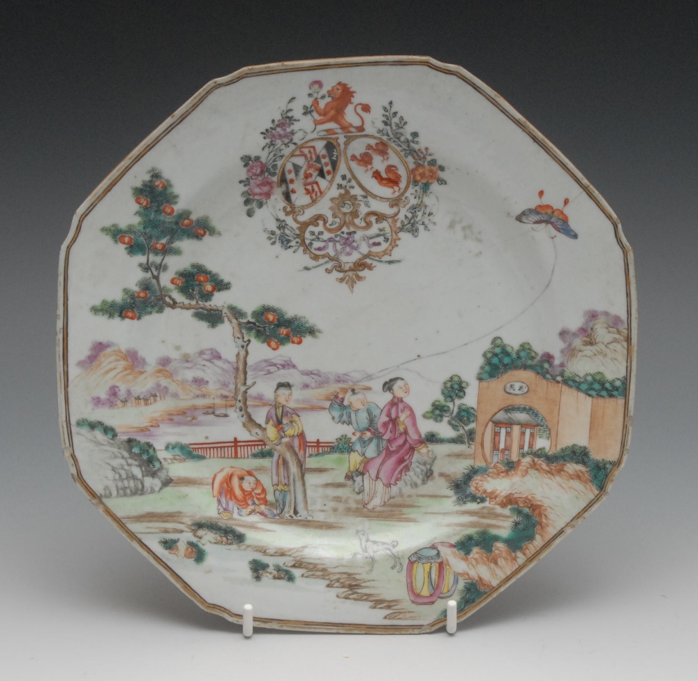 A Chinese Famille Rose Armorial octagonal plate, painted with figures in a garden, flying a kite,