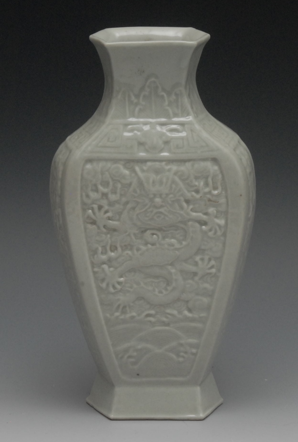 A Chinese pale celadon flattened ovoid vase, moulded with a fierce dragon above the waves, spreading